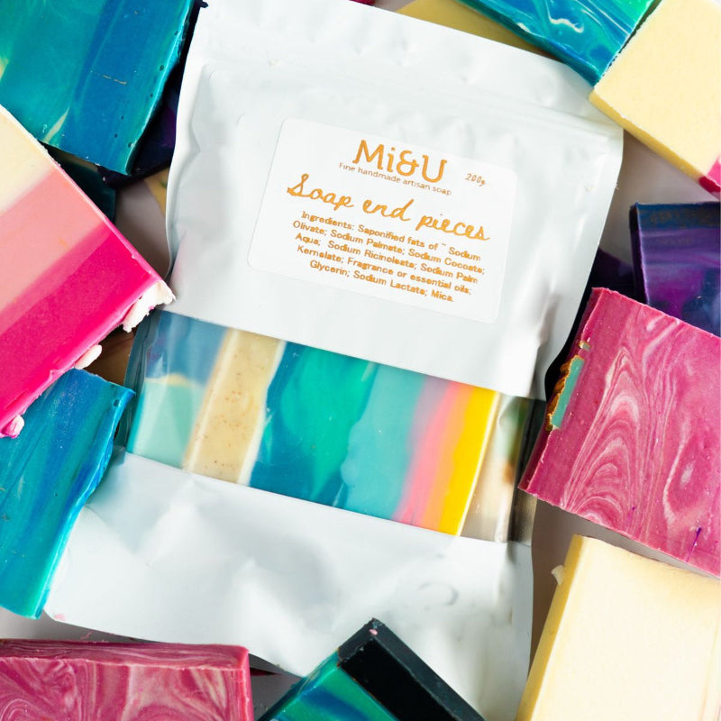 Colorful soap bars with a white packaging labeled 'Mi&U' on a marble surface.
