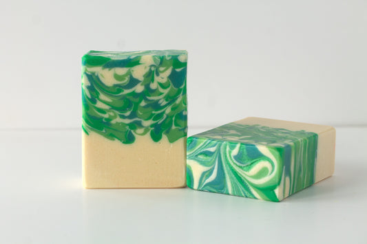Two bars of green and beige marbled soap on a white background