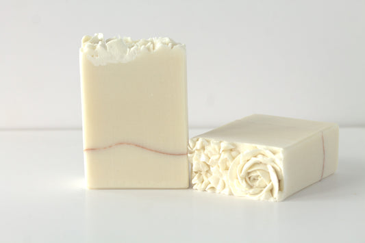 Two bars of white soap with hand piped flowers on a white surface