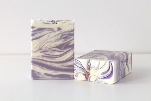 Two bars of marbled soap with purple and white swatches on a light gray background