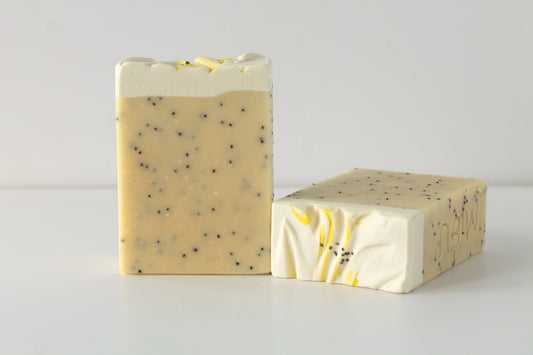 Two bars of soap with poppy seeds on a light gray background