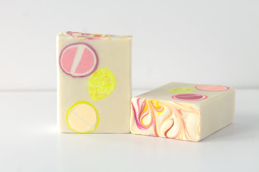 Two bars of soap with colorful citrus designs and swirls on a white background