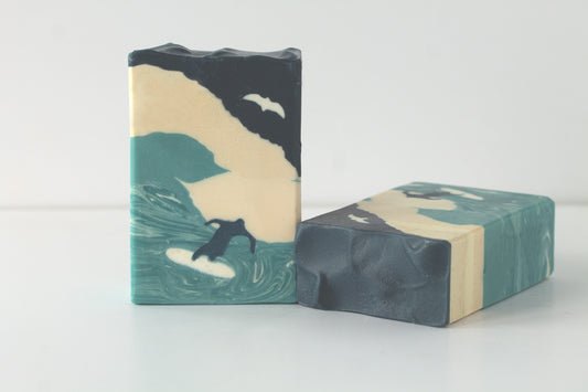Two men's soap bars with a man surfing on a white background