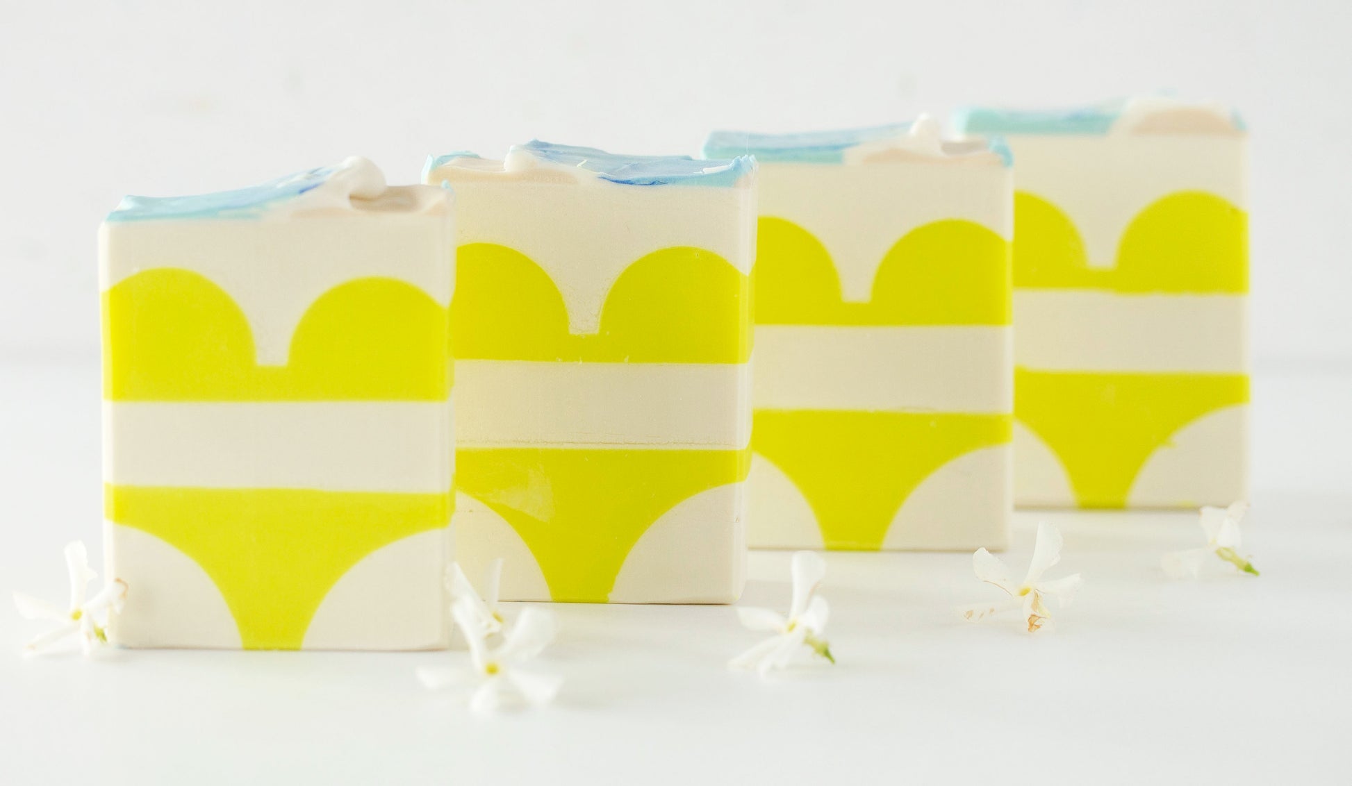 Four soap bars with yellow and white bikini design on a white background