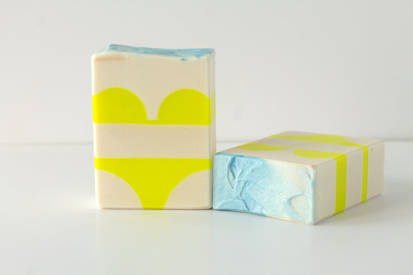 Two soap bars with a bikini design on a white background with an beach soap top
