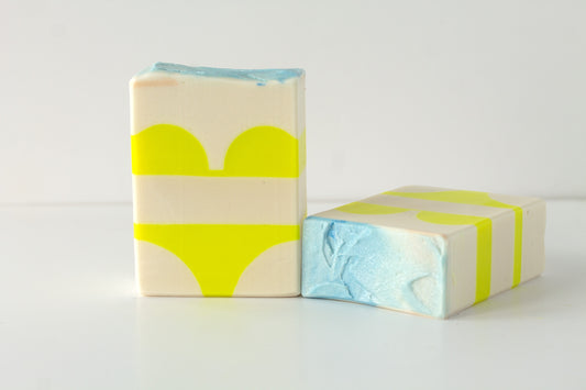 Two soap bars with a bikini design on a white background with an beach soap top
