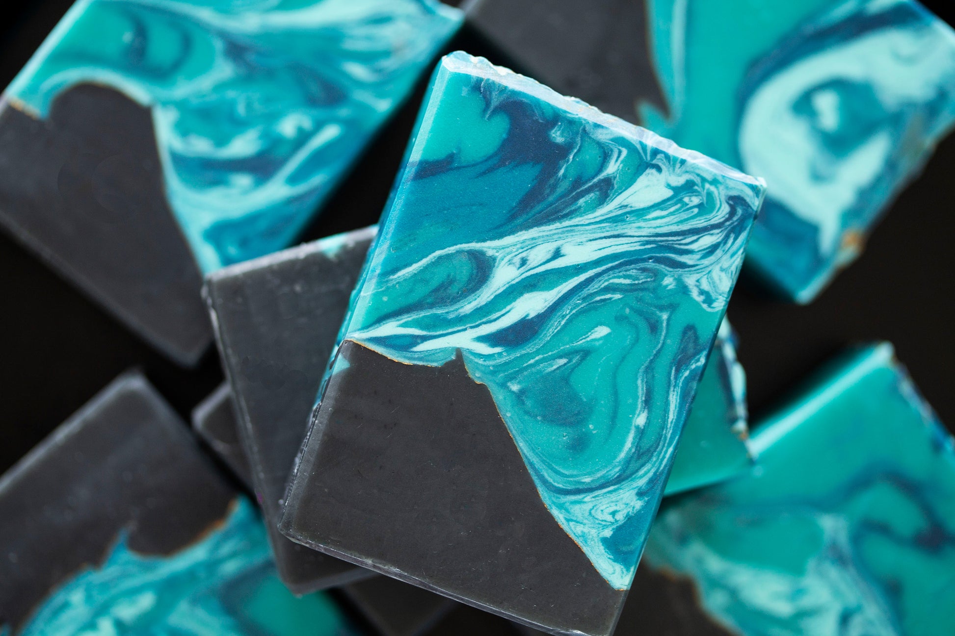 Close-up of teal and black marbled soap bars on a dark background