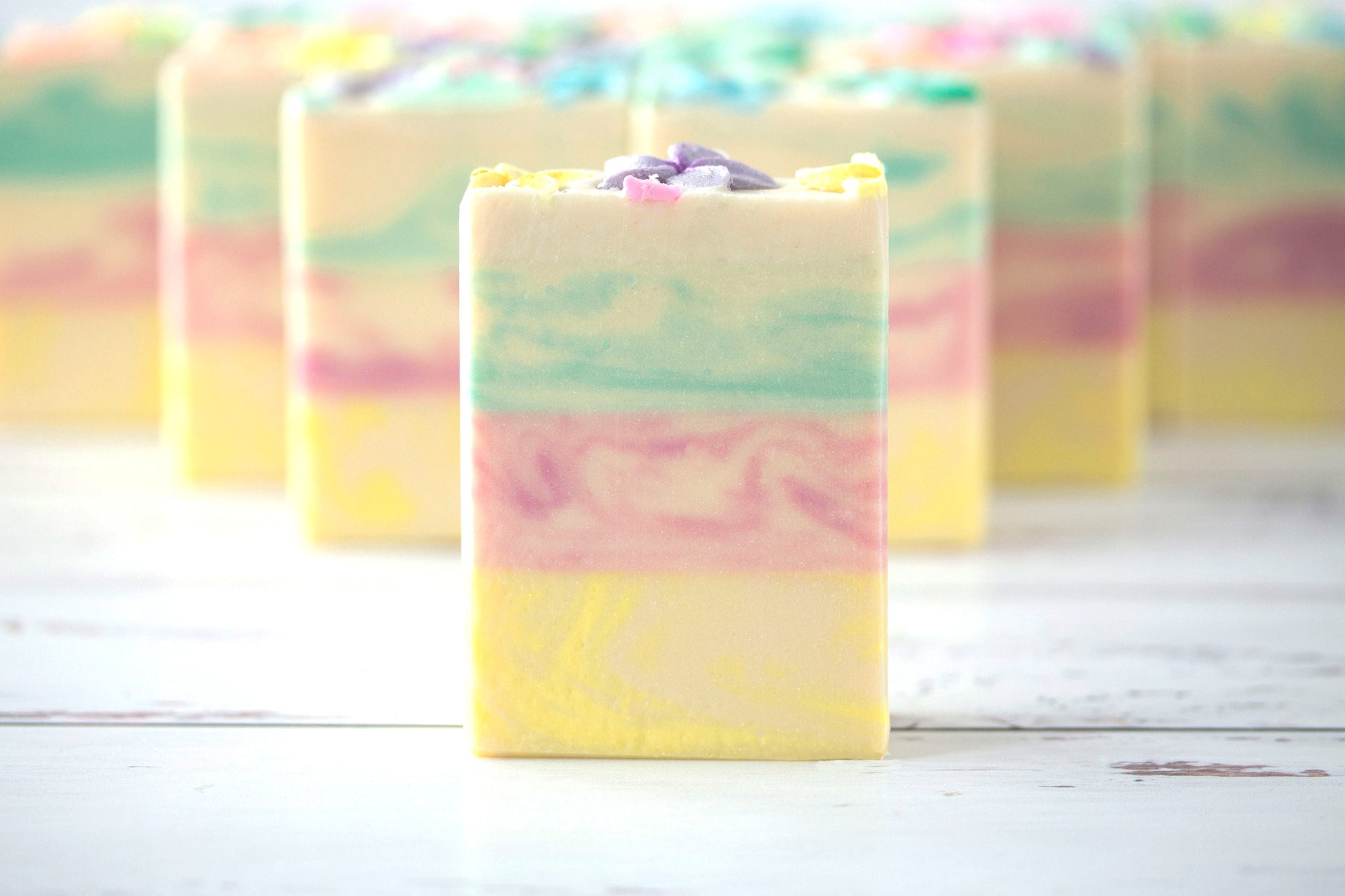 Pastel-colored soap bars on a white wooden surface