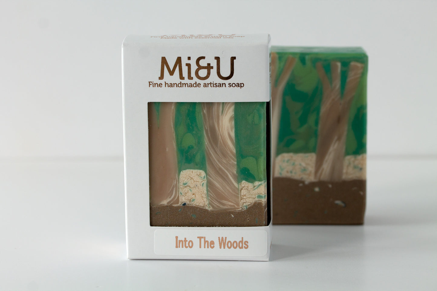 Handmade artisan soap with packaging labeled 'Mi&U Into The Woods' on a white background