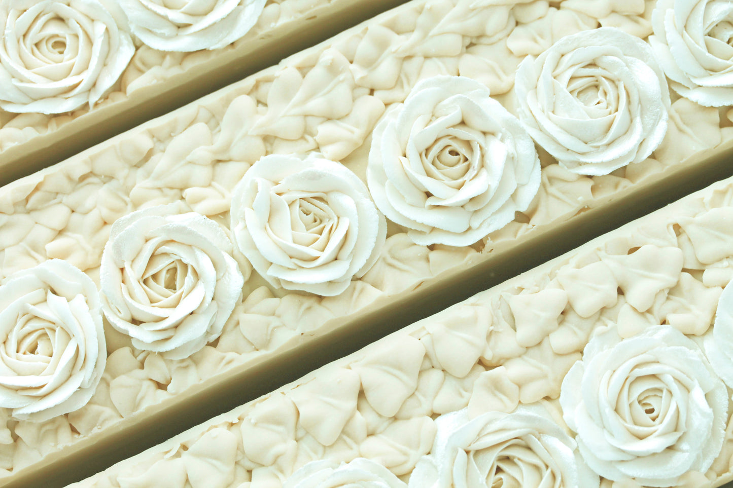 Close-up of white piped soap roses on a soap loaf with a gold background