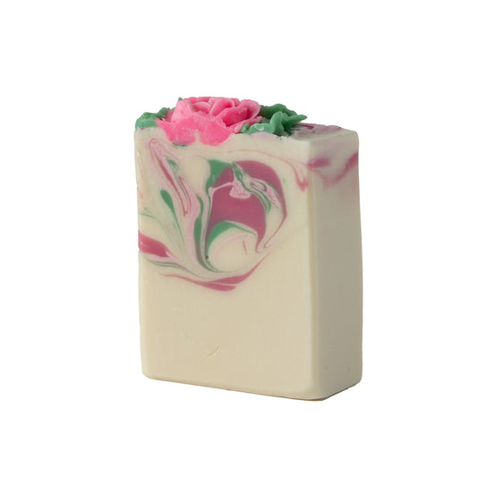 Bar of soap with pink and green swirls and a pink flower on top against a white background
