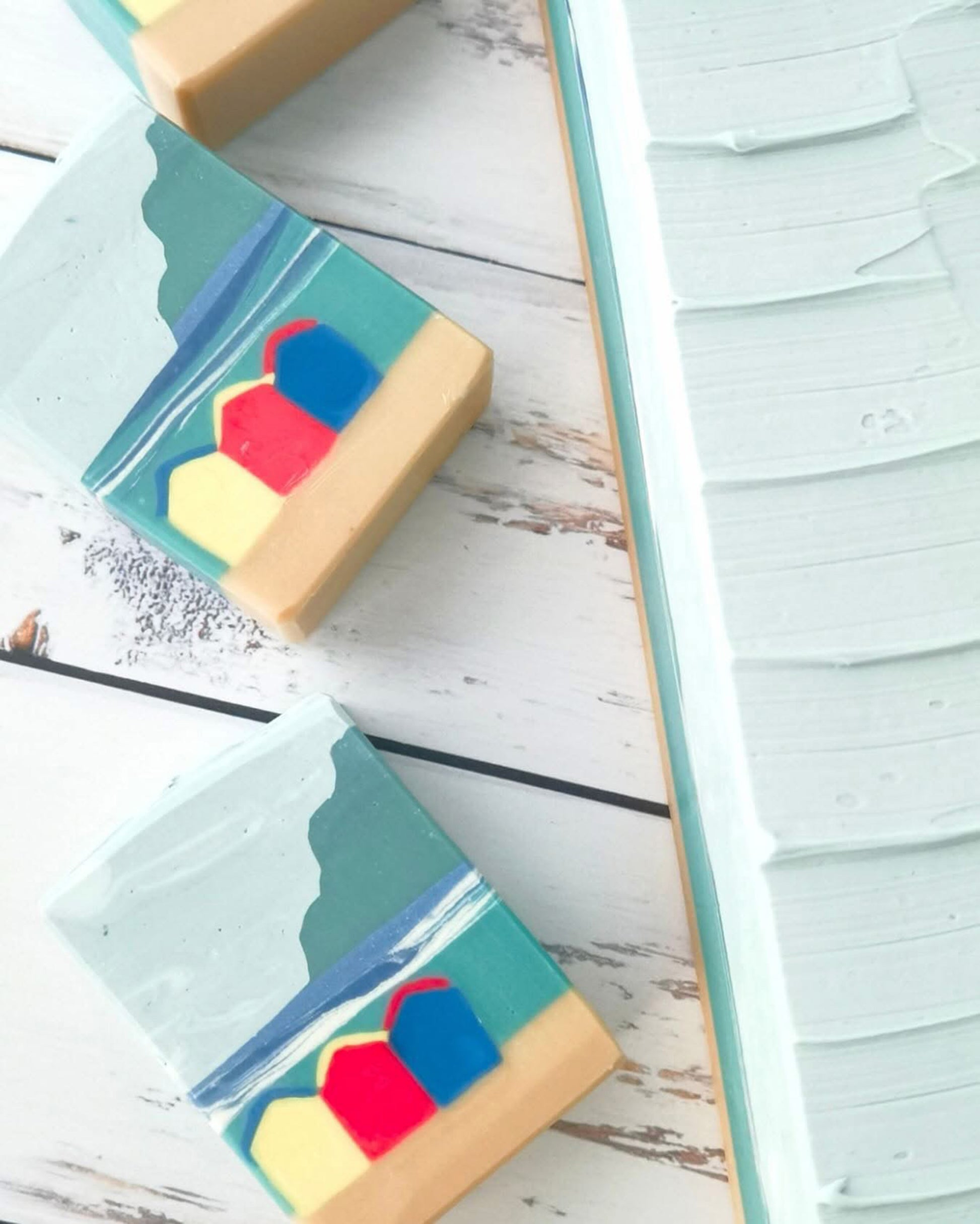 Colorful beach theme soaps on a wooden surface with a textured soap top on a soap loaf the background