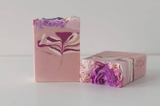 Two bars of soap with piped peony soap flowers on a white surface