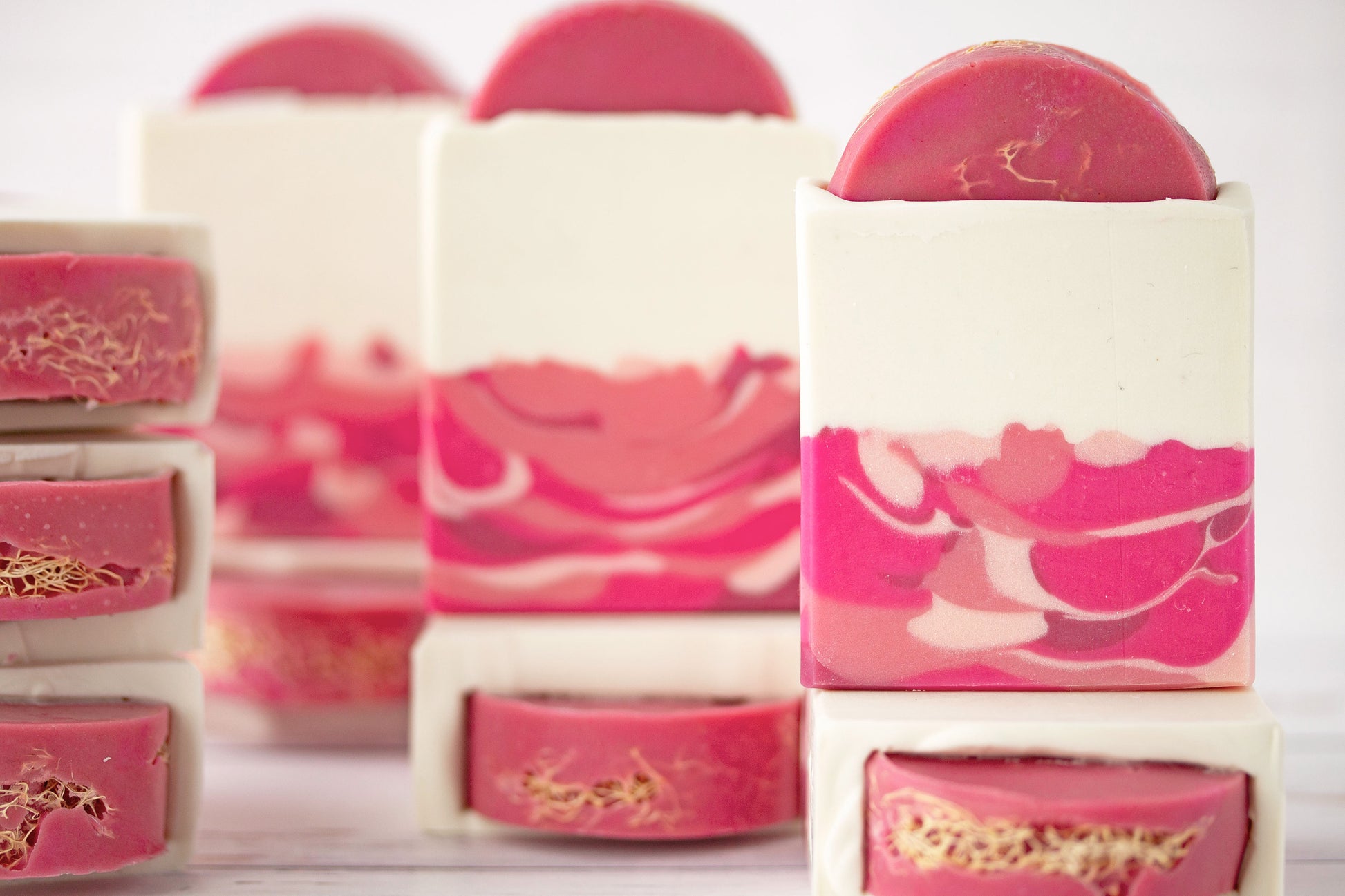 Stacked loofah soaps with pink and white marbled swirls.