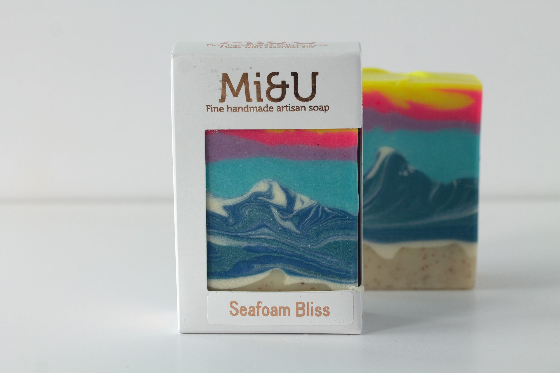 Mi&U handmade artisan soap with an ocean inspired design next to its packaging on a white background