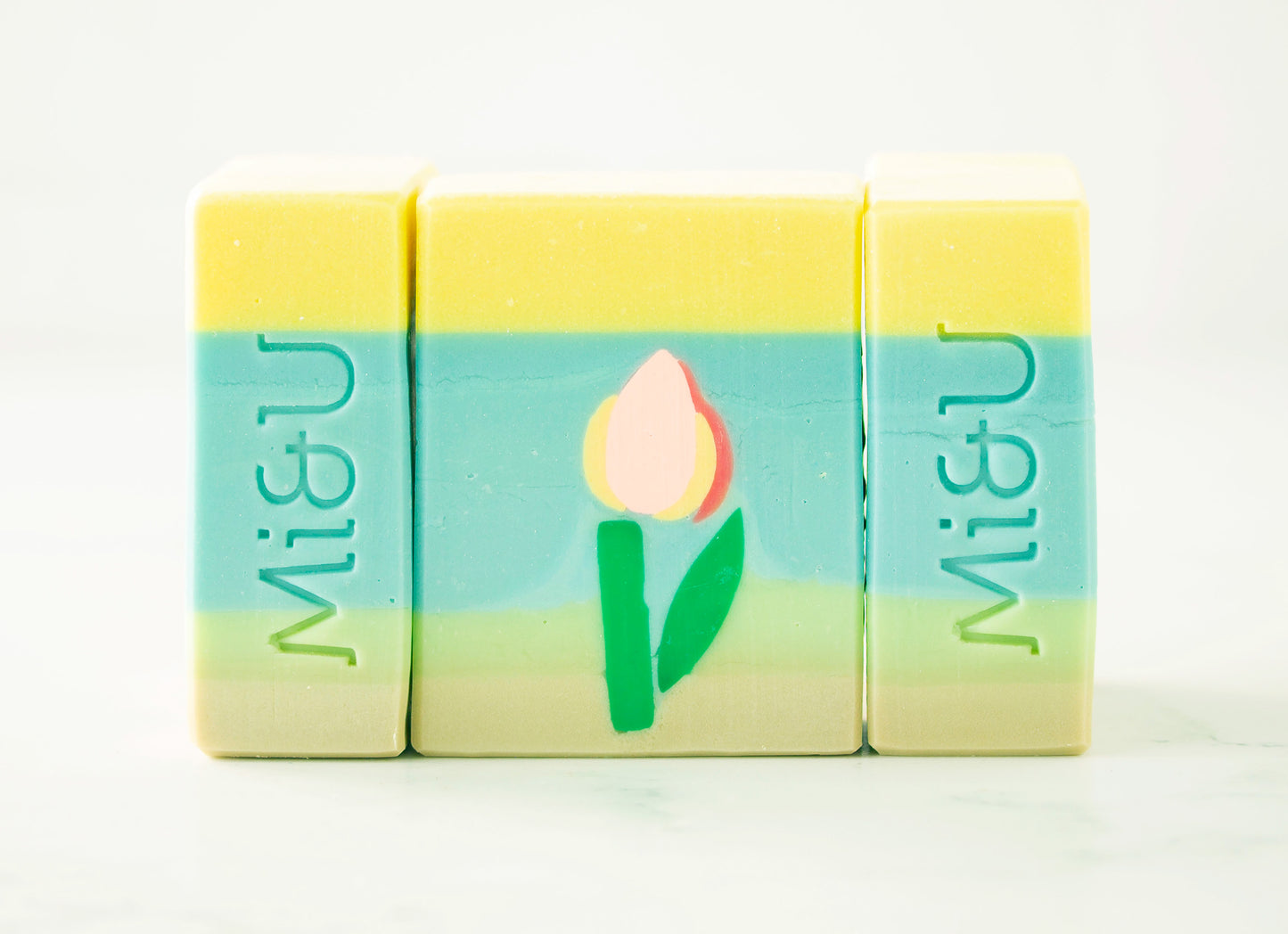 Three colorful soap bars with a tulip design and 'Mi&U' branding on a white background.