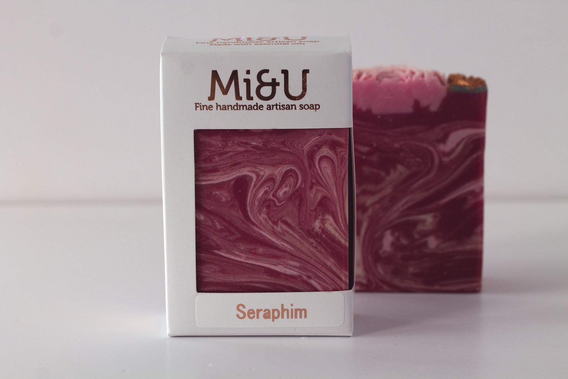 Marbled red and pink soap in 'Mi&U' packaging on a white background