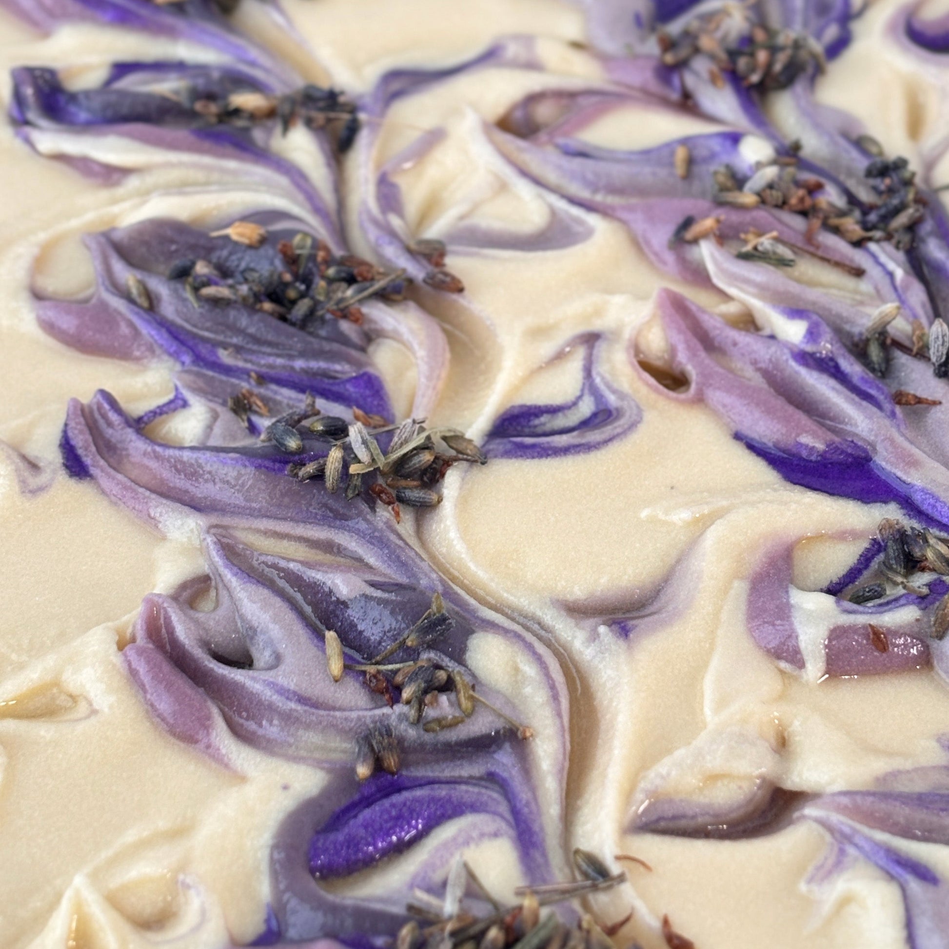 Close-up of a soap bar with purple and white swirls and lavender buds