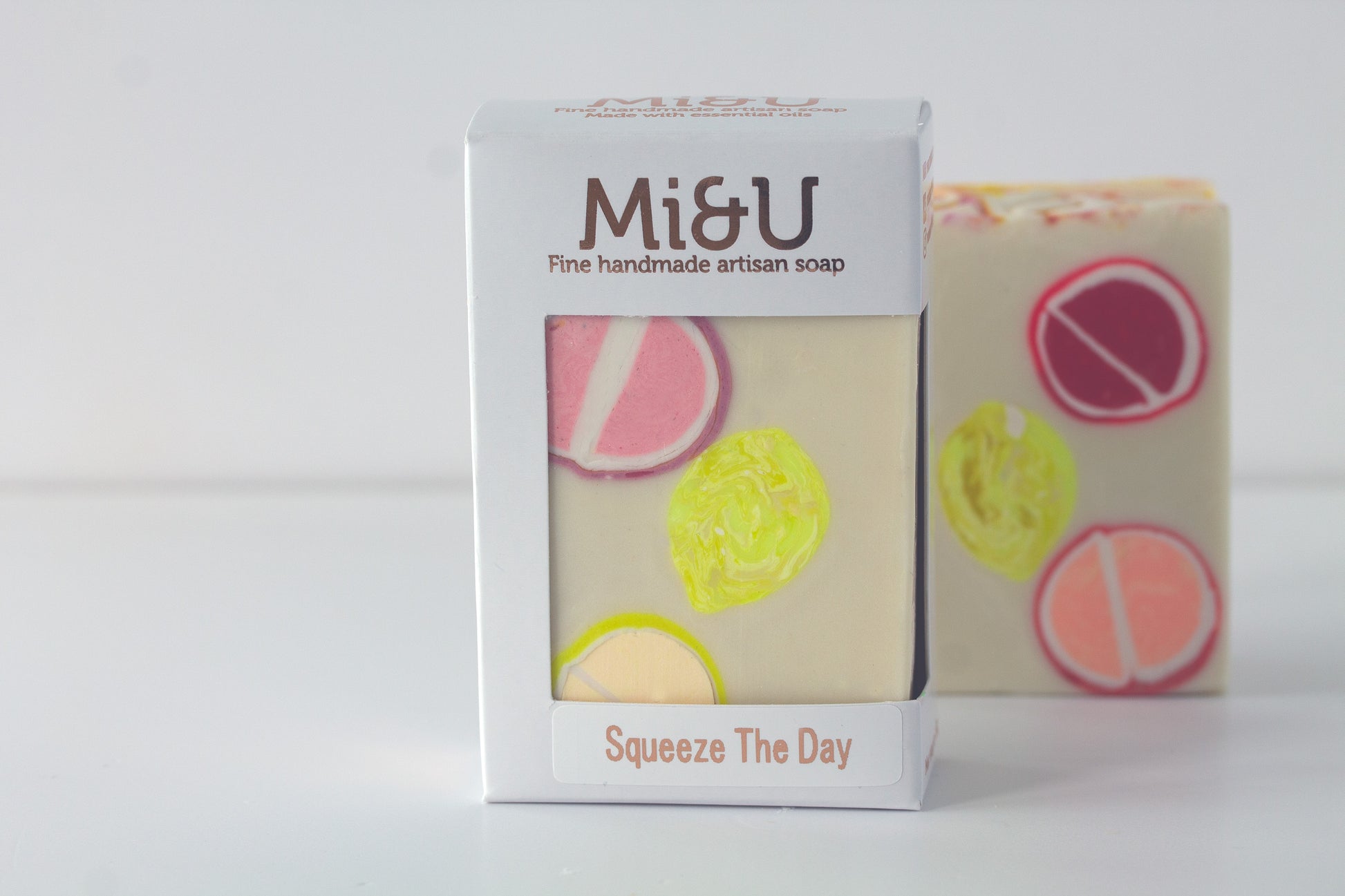 Handmade artisan soap with colorful design and Mi&U packaging on a white background